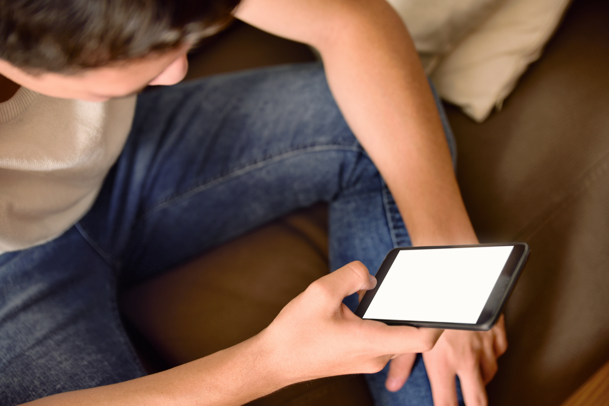Young boy on a couch using a smartphone in the living room.